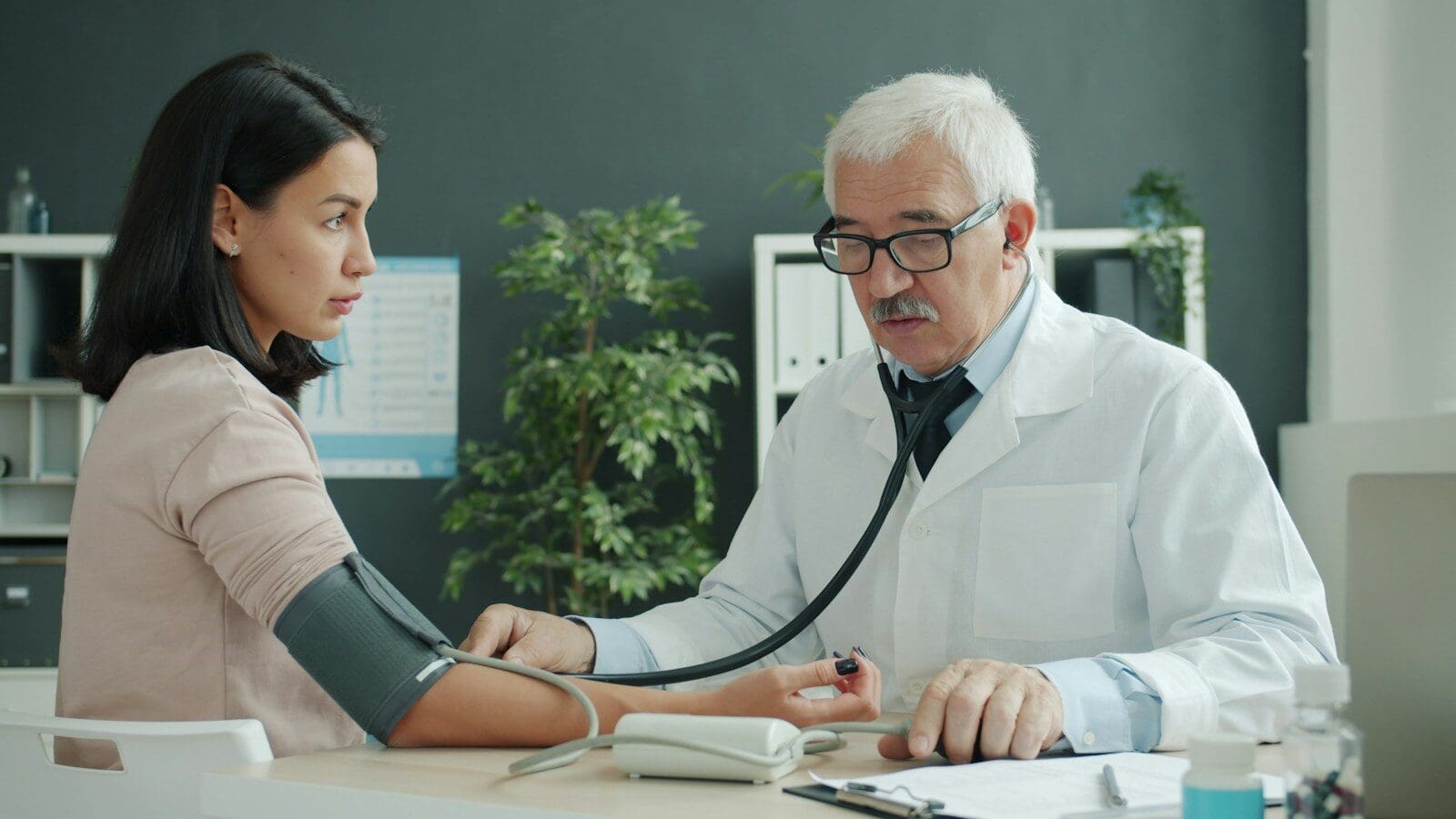 Doctor checks patient's blood pressure with stethoscope